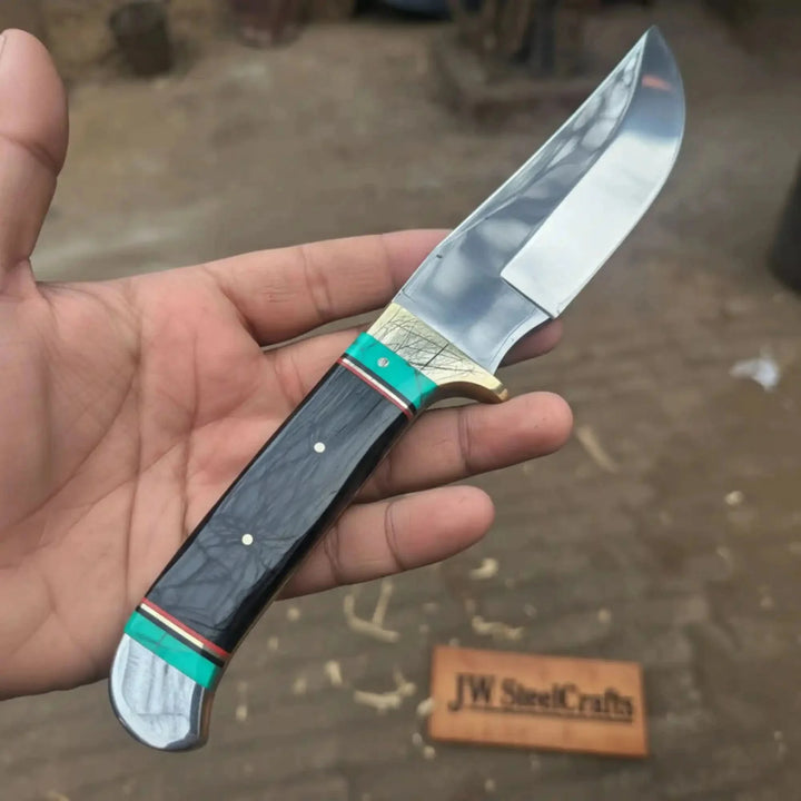 Nightlight Hunter Satin Fixed Blade Frontier Bowie Knife Hand Holding A Knife With A Decorative Handle, Blurred Background