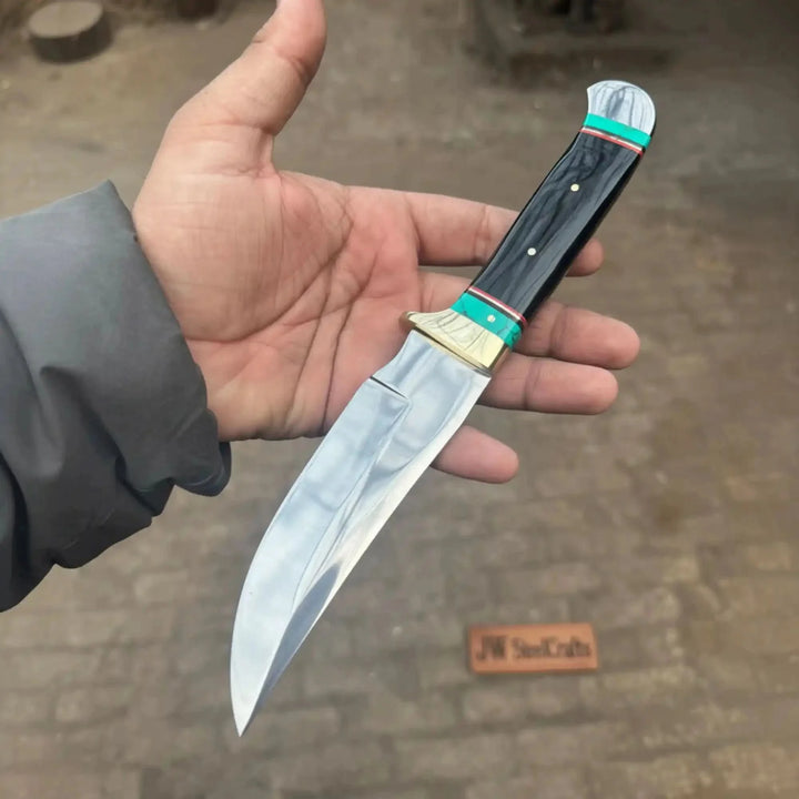 Nightlight Hunter Satin Fixed Blade Frontier Bowie Knife Hand Holding A Knife With A Decorative Handle On A Blurred Background