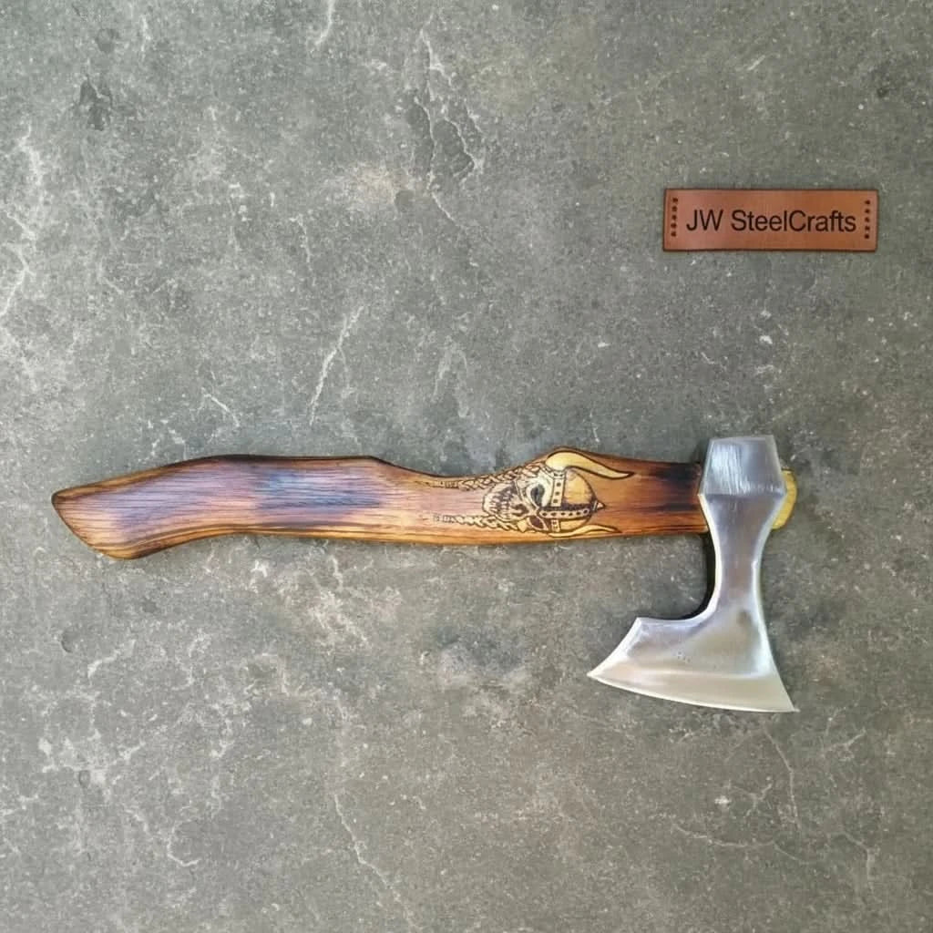     Traditional Norse-inspired axe with engraved Viking skull detail on the wooden handle and polished steel cutting edge.
