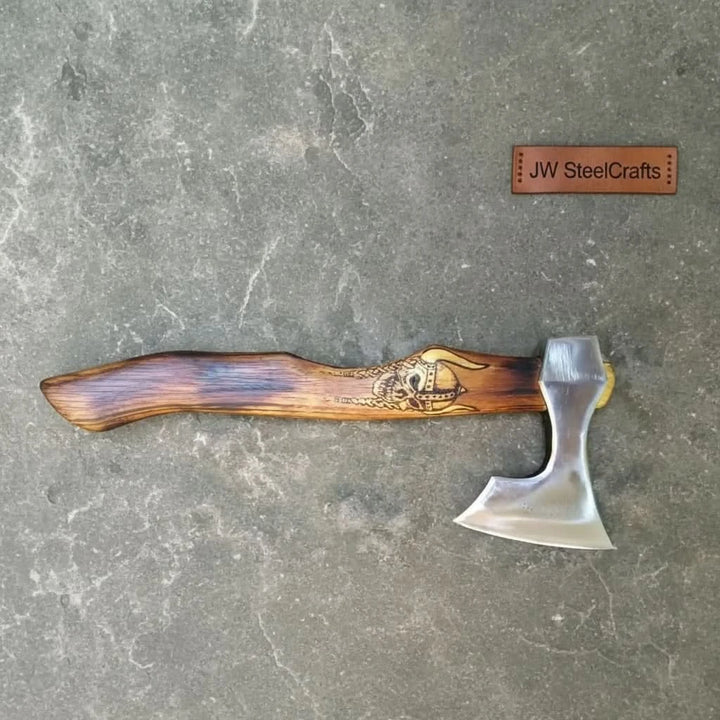     Traditional Norse-inspired axe with engraved Viking skull detail on the wooden handle and polished steel cutting edge.
