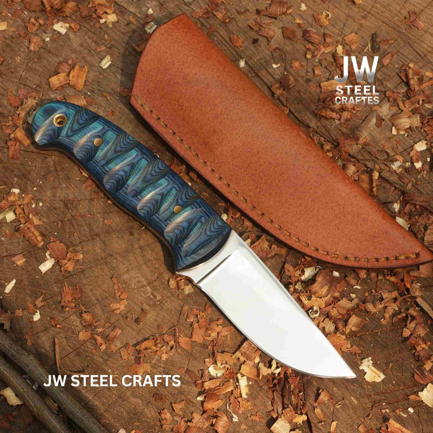 Knife with blue handle and leather sheath on a wooden surface with 'JW Steel Crafts' branding.
