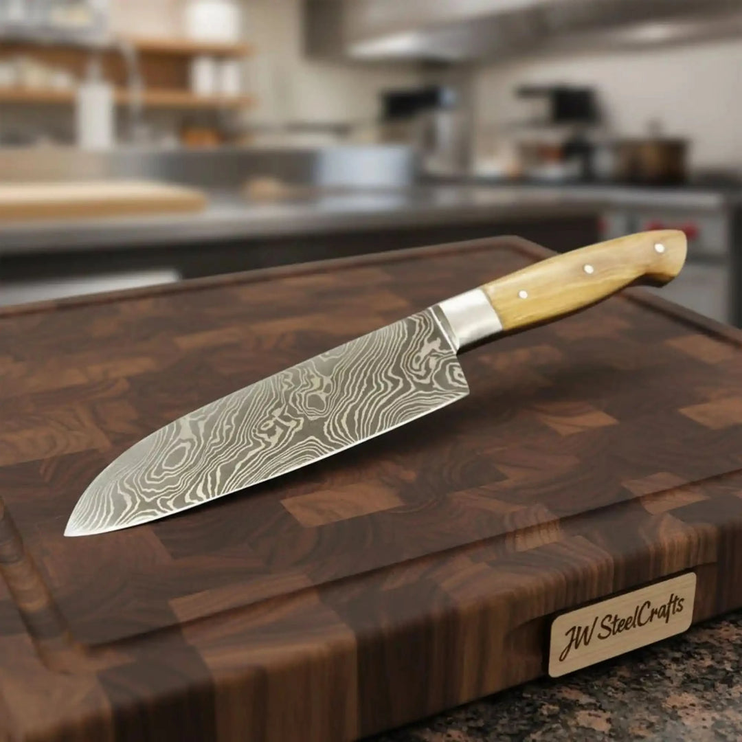 Sharp patterned steel chef knife placed on a dark walnut cutting surface
