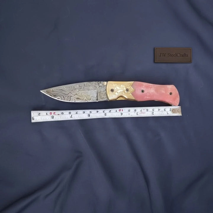     Rubyedge folding blade featuring pink handle and artistic Damascus steel pattern for outdoor everyday carry
