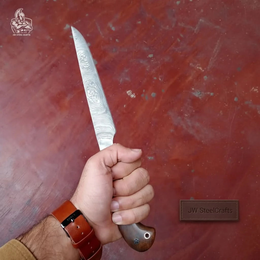 Handheld Damascus dagger with wooden handle shown over a reddish tabletop background