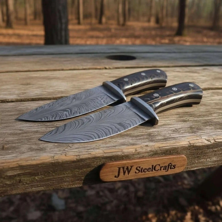 Forest stump matching Damascus knives by JW SteelCrafts with black handles and brown leather sheath.