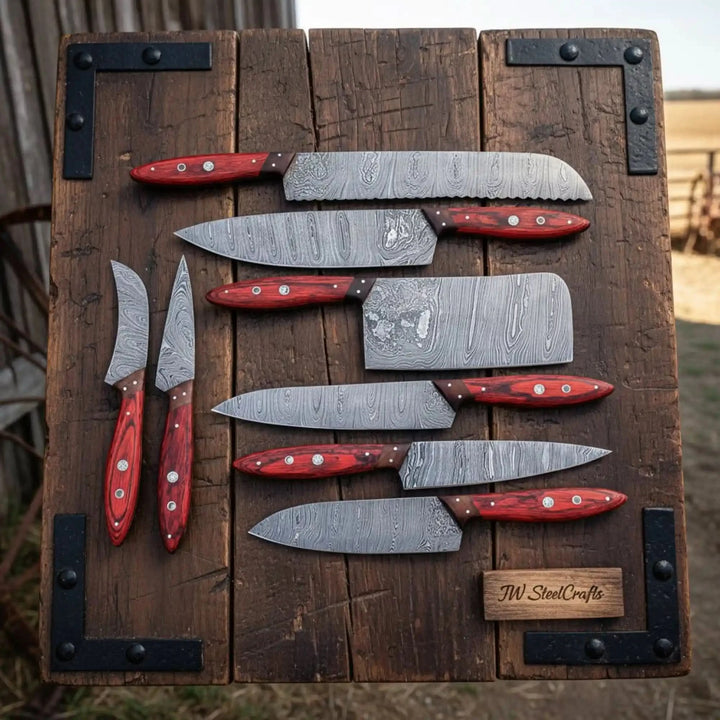 Elegant Damascus steel kitchen knives captured from overhead perspective highlighting layered steel grain and rich red woodgrain handles.