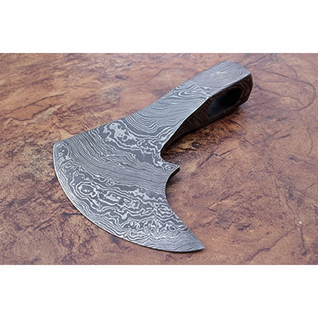     Custom Damascus Viking axe head with curved bearded edge and detailed layered steel patterns on outdoor stone display.