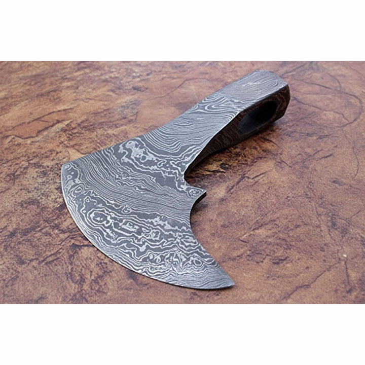     Custom Damascus Viking axe head with curved bearded edge and detailed layered steel patterns on outdoor stone display.