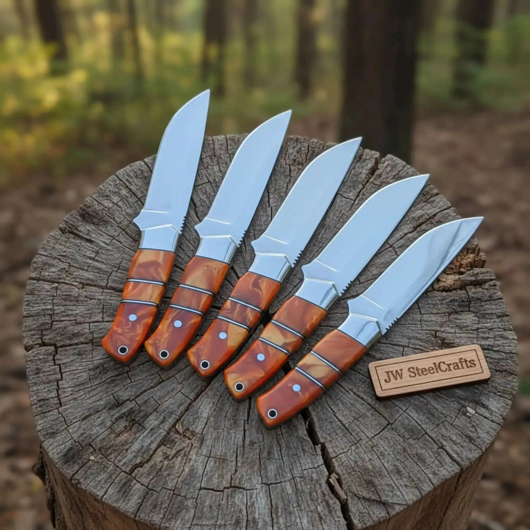 Standing bold on a forest stump, five hunting knives with vivid orange swirl handles and prominent serrated spine guards