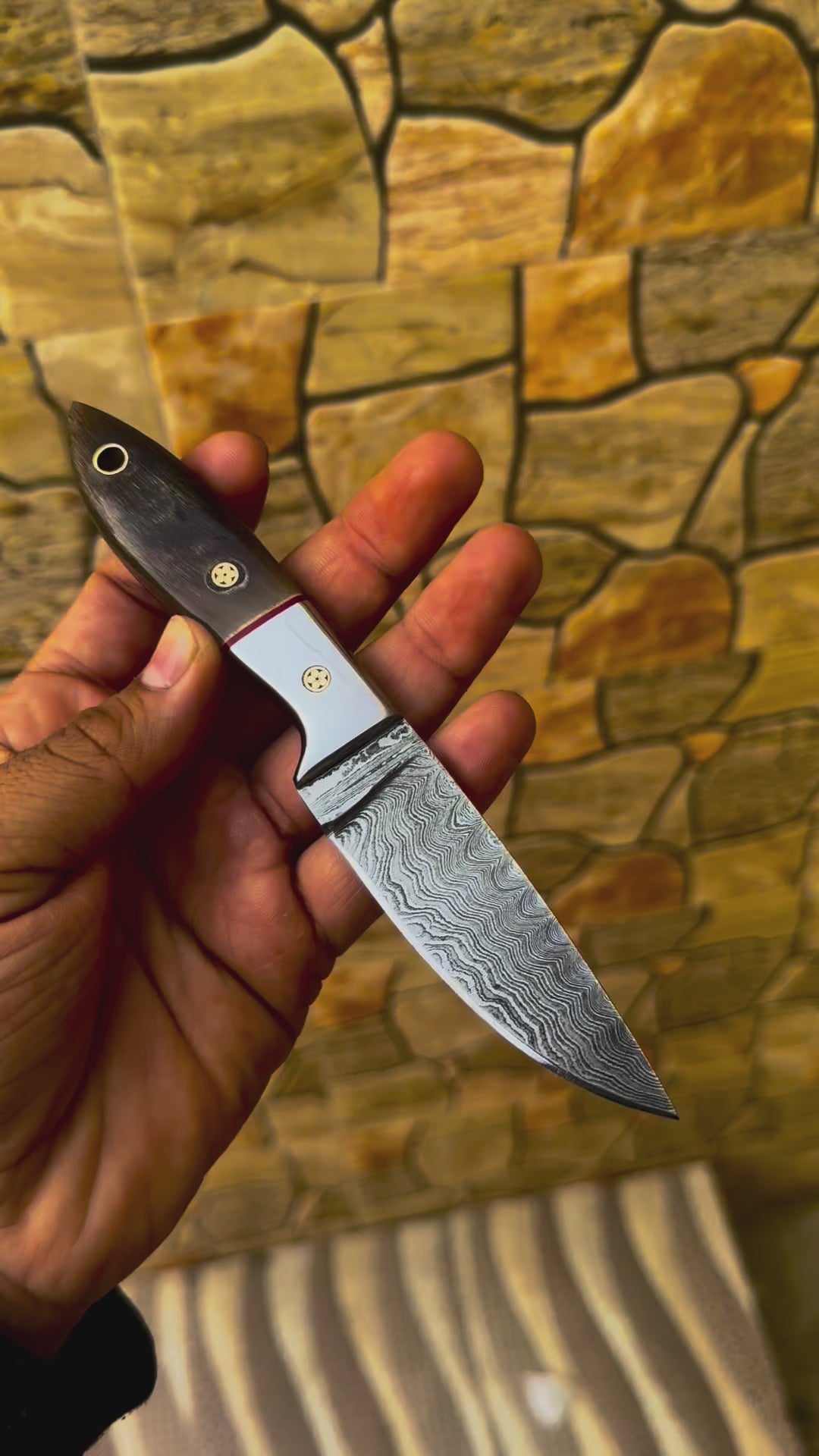 Custom Damascus steel skinner hunting knife with polished bull horn handle, brass pins, and leather sheath.