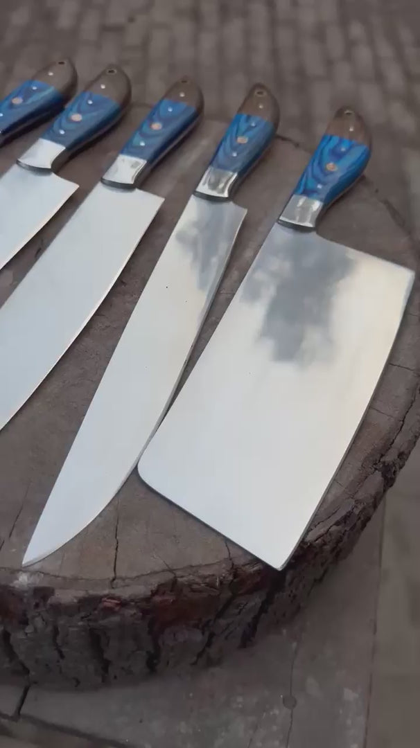 A high-definition showcase video of a handmade 5-piece chef knife set with vibrant blue wood handles. The video features close-ups of the sharp full-tang blades and ergonomic grips, displayed in a rustic outdoor farm setting.