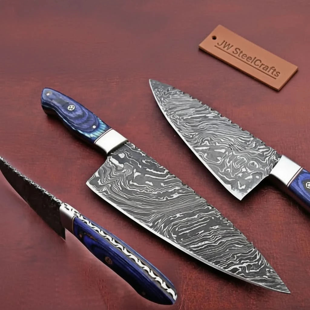 Blue resin handle chef knife set displayed on brown wood with three patterned blades