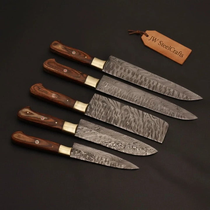 High end kitchen cutlery collection displayed on matte black backdrop with decorative layered steel blade patterns.