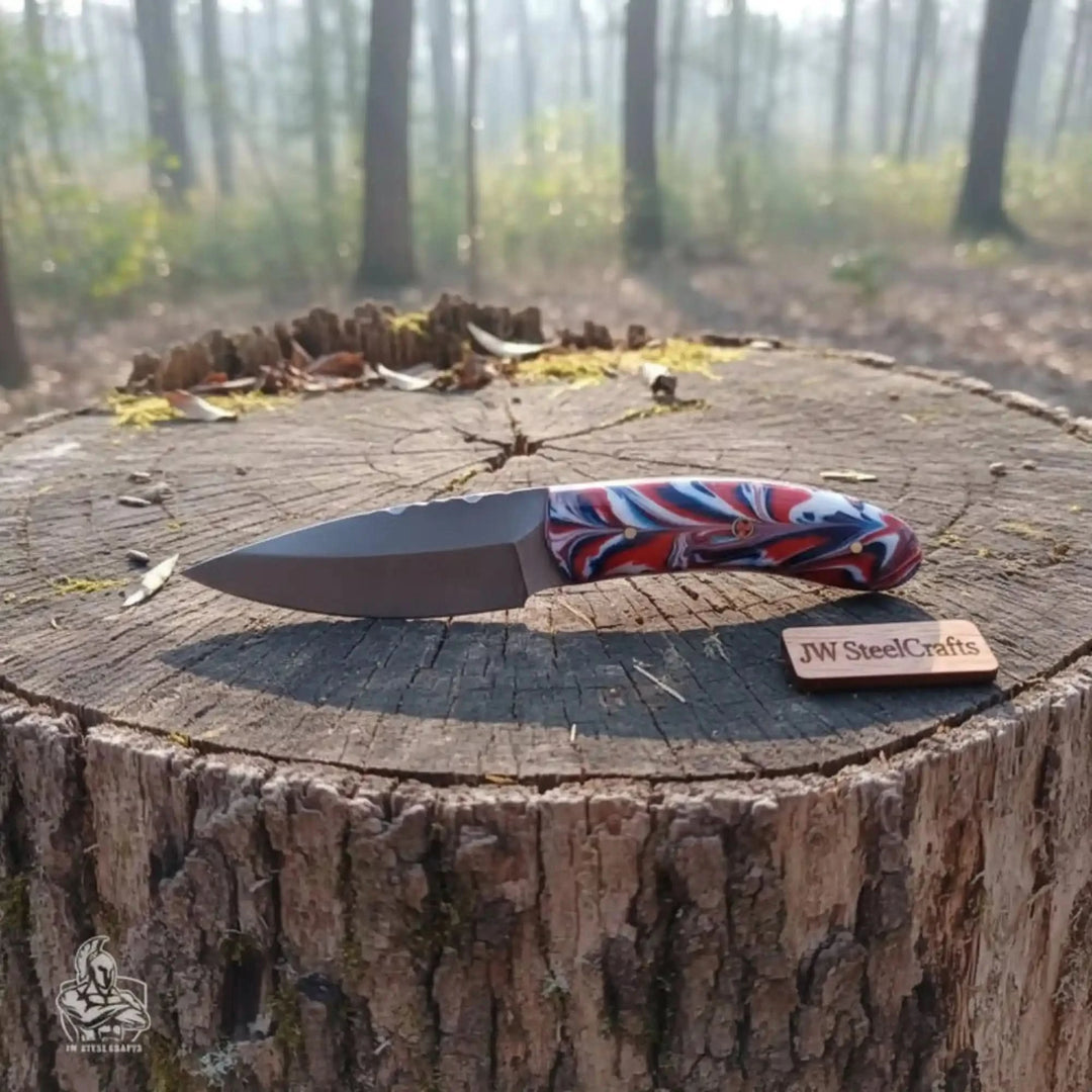resin handle knife display showing a dark blade and colorful red blue grip on a forest tree stump.