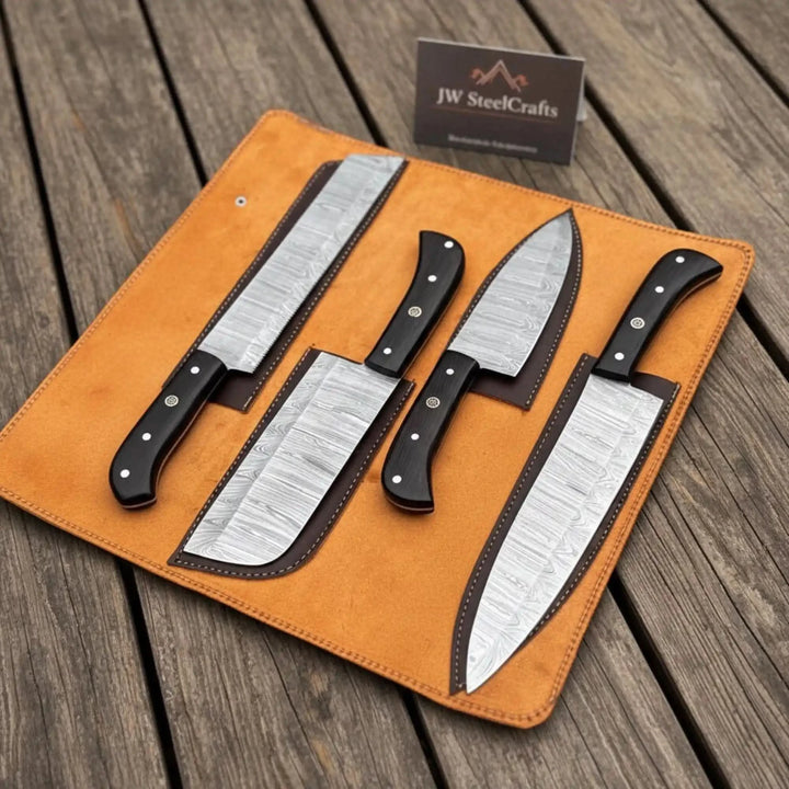 branded Damascus chef knife collection with dark ebony grips and layered steel blades arranged in an unrolled amber leather case in an outdoor forge setting

