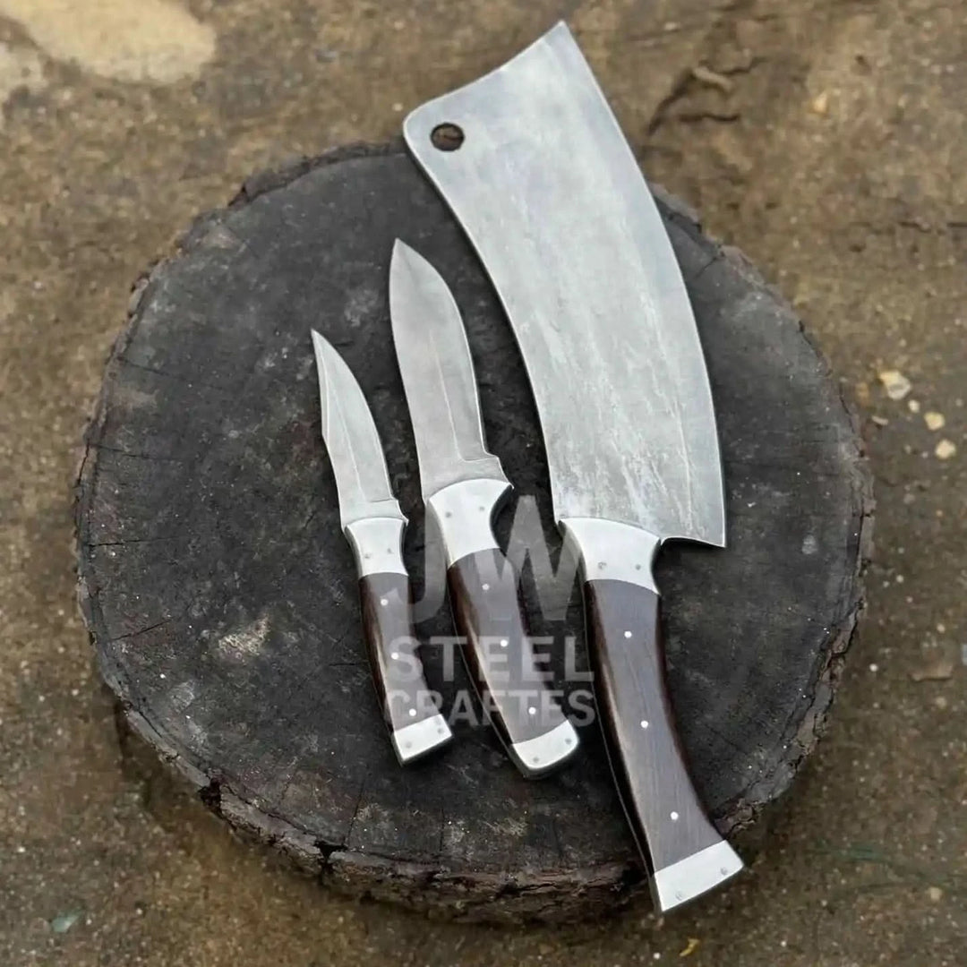 Forged butcher cleaver with utility and detail knives displayed in outdoor workshop setting
