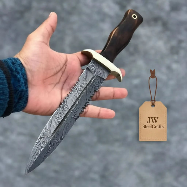 Handheld survival knife with Damascus blade pattern and dark wood handle outdoors