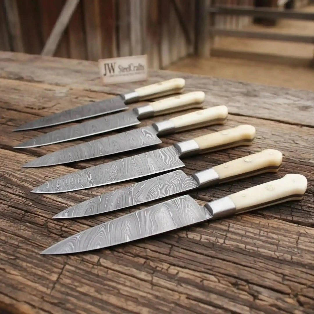 Parallel chef knives with cream grips and patterned Damascus blades displayed in rows