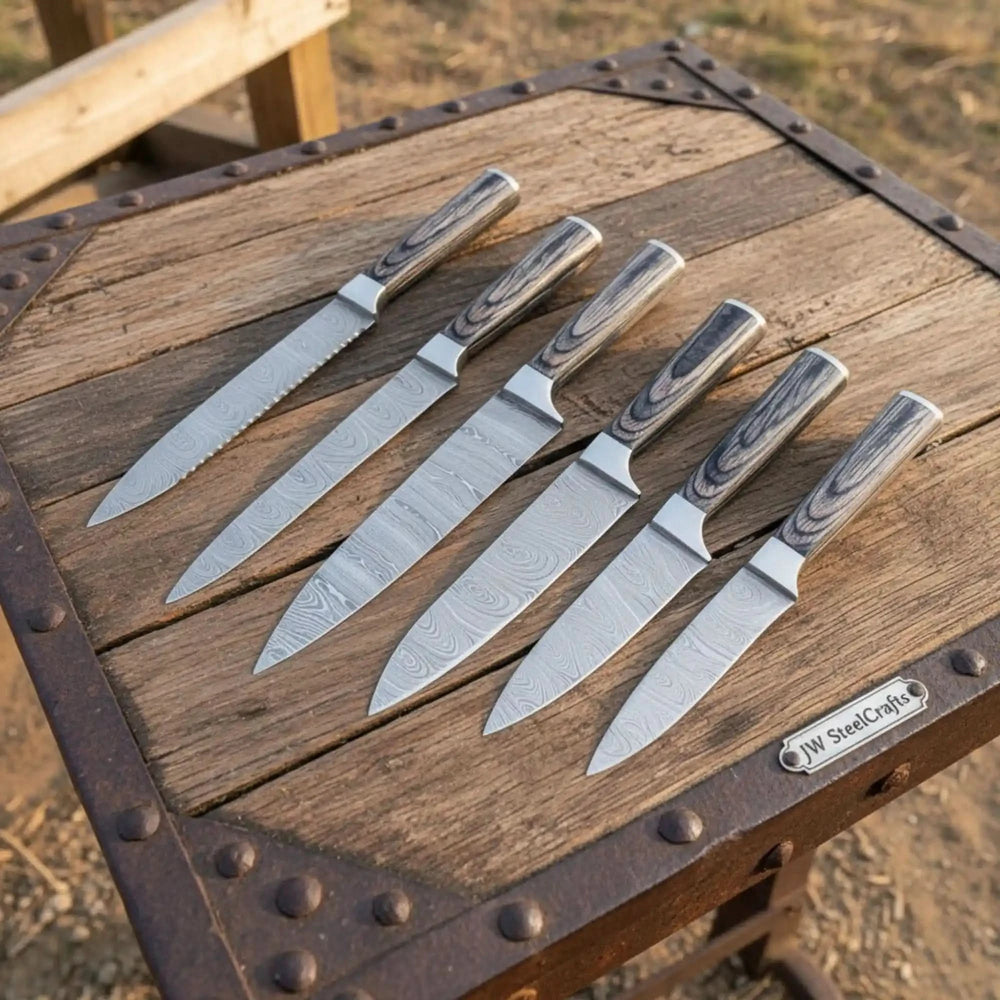 Polished Damascus chef tools arranged diagonally to emphasize blade shape and layered steel craftsmanship.