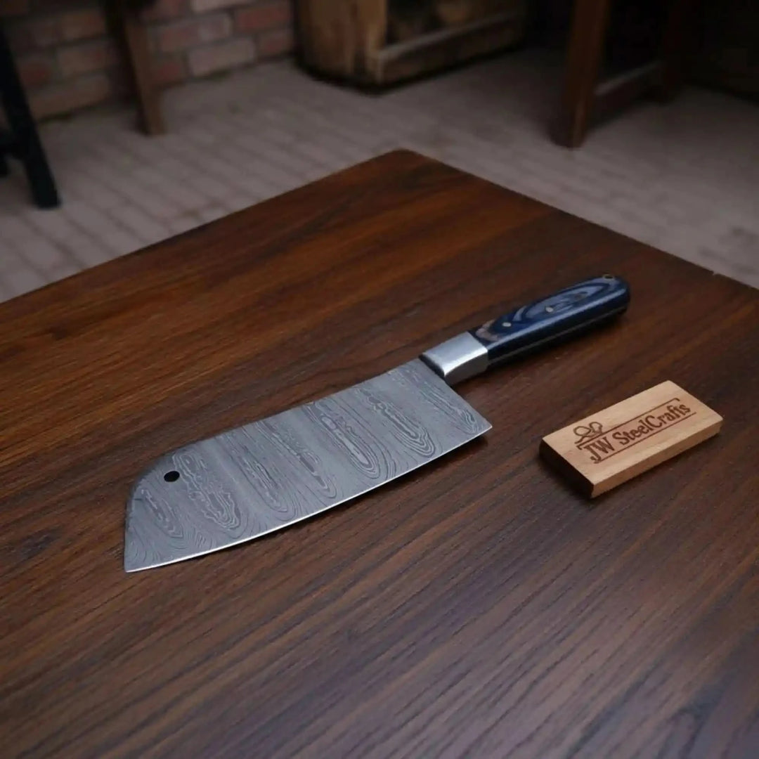 Rectangular Damascus kitchen cleaver featuring a hole near the blade tip and blue grip