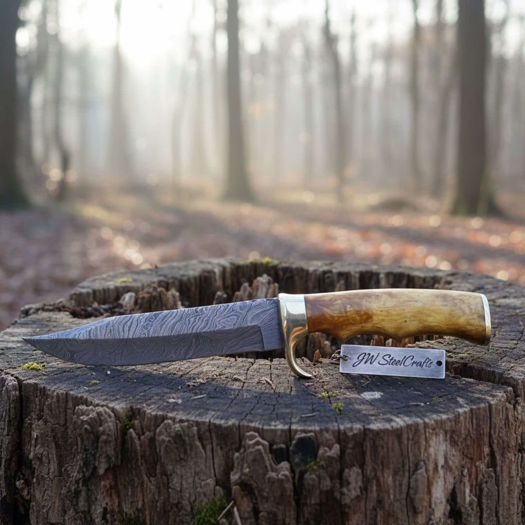     Classic Bowie camp knife with layered steel blade and handcrafted wooden grip outdoors