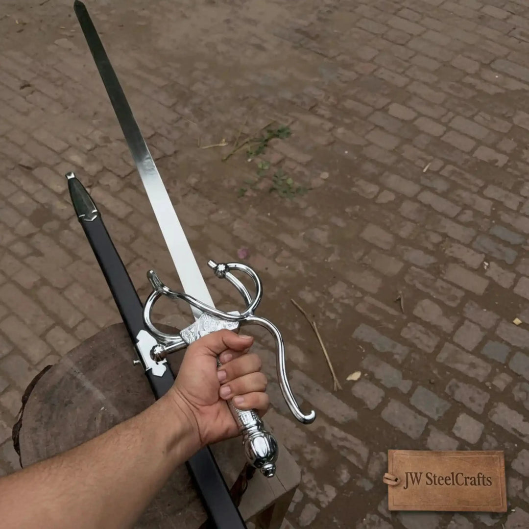 Close-up of a person holding a decorative silver rapier with an elaborate swept basket guard and engraved crossguard