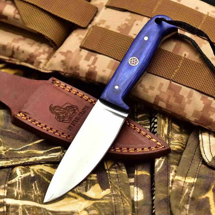 Bushcraft knife trio with pink, black, and blue handles, black braided lanyards, and stitched brown leather sheaths.