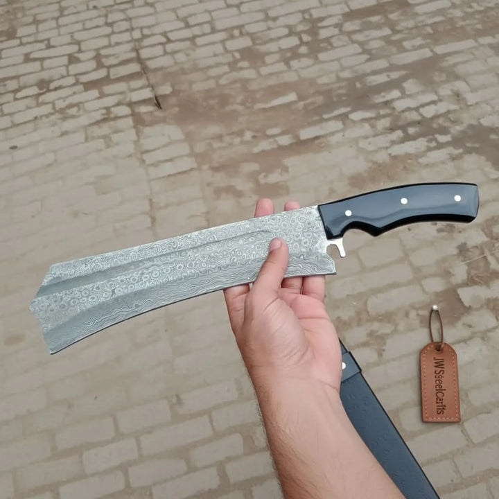 Oversized Tanto knife with black handle, white pins, Damascus patterned blade, and custom made product styling
