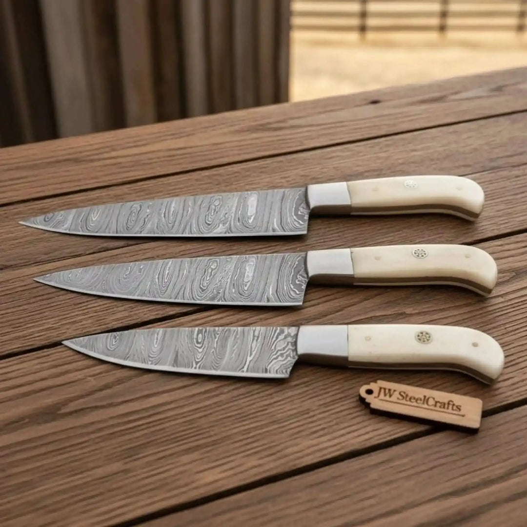 Matching ivory grip kitchen knives with patterned steel blades and silver bolsters