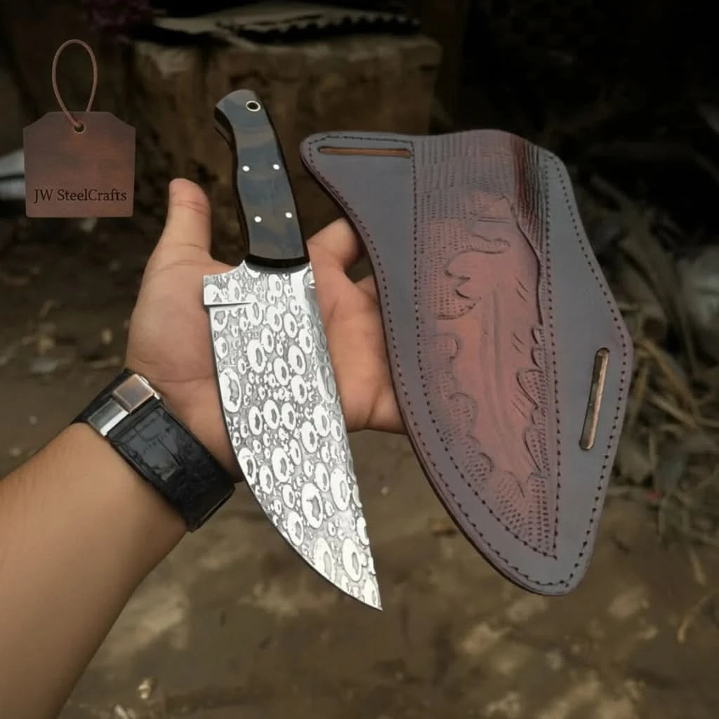 Handheld skull blade knife and leather sheath display with a JW SteelCrafts brand tag in the background.