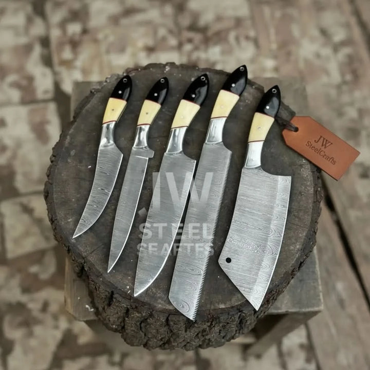 Top view of 5 piece Damascus chef knife set with camel bone and black micarta handles on tree stump
