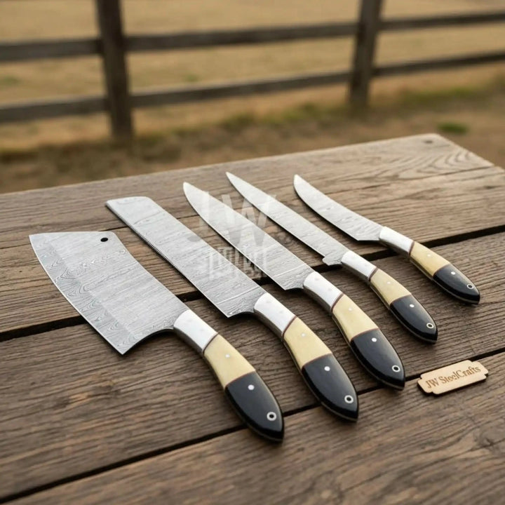 Top-down view of a 5-piece handmade Damascus steel chef knife set with elegant cream and black resin handles, neatly arranged on a rustic wooden table.