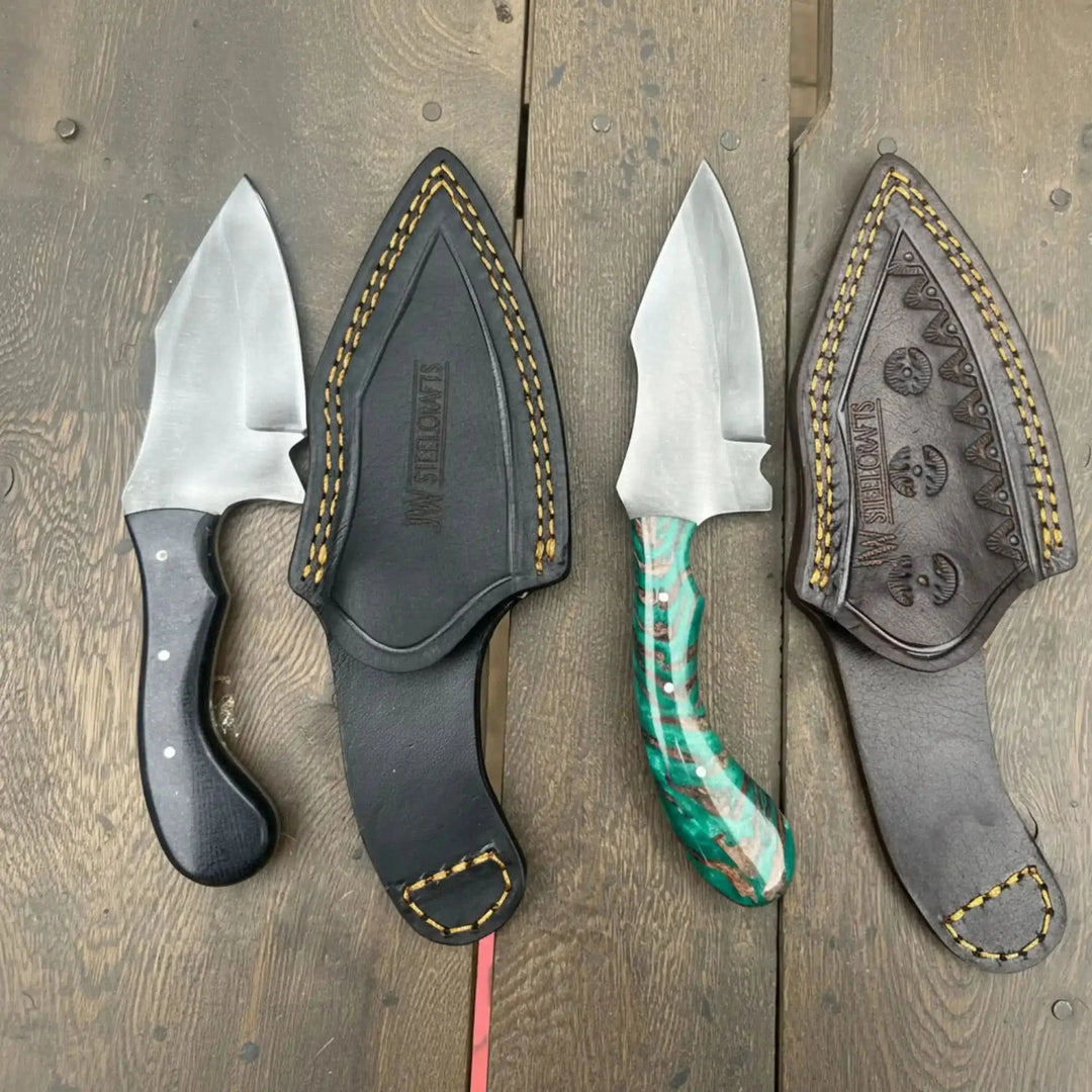 Tracker axe skinner knife set featuring two knives with leather sheaths displayed on a wooden surface.