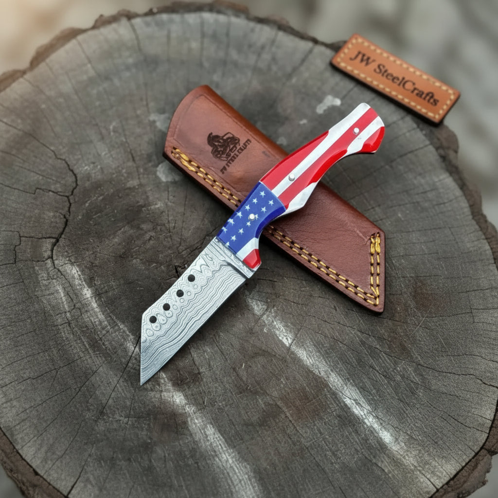 Damascus steel knife with USA flag handle, red white and blue grip, brown leather sheath, and tree stump display.