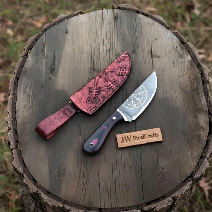 Knife with leather sheath and engraved blade on a wooden surface, branded &