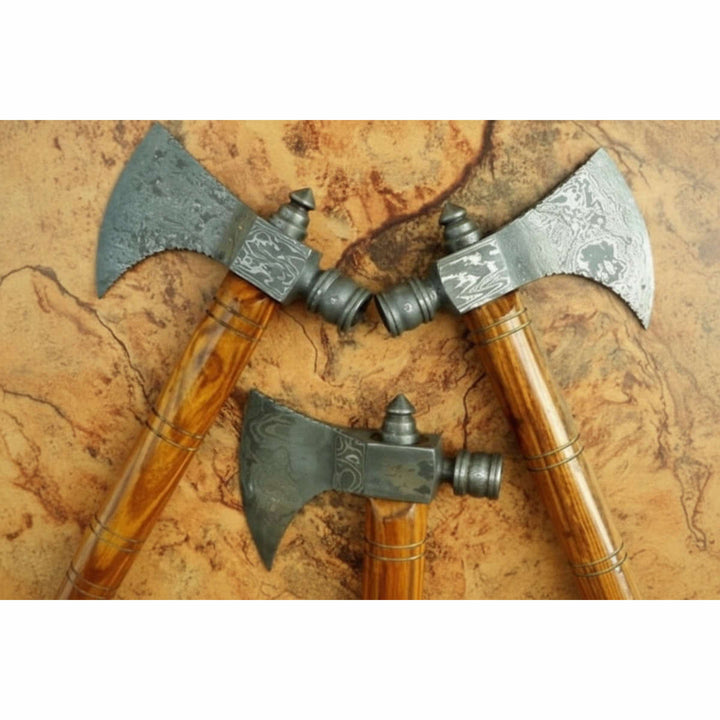     Rustic Norse throwing axes with artisan forged steel heads and smooth tapered wood handles on vintage tabletop background.