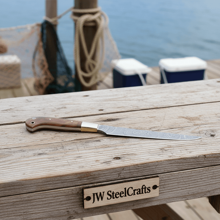 Slender curved blade fillet knife with brass bolster and brown handle near water