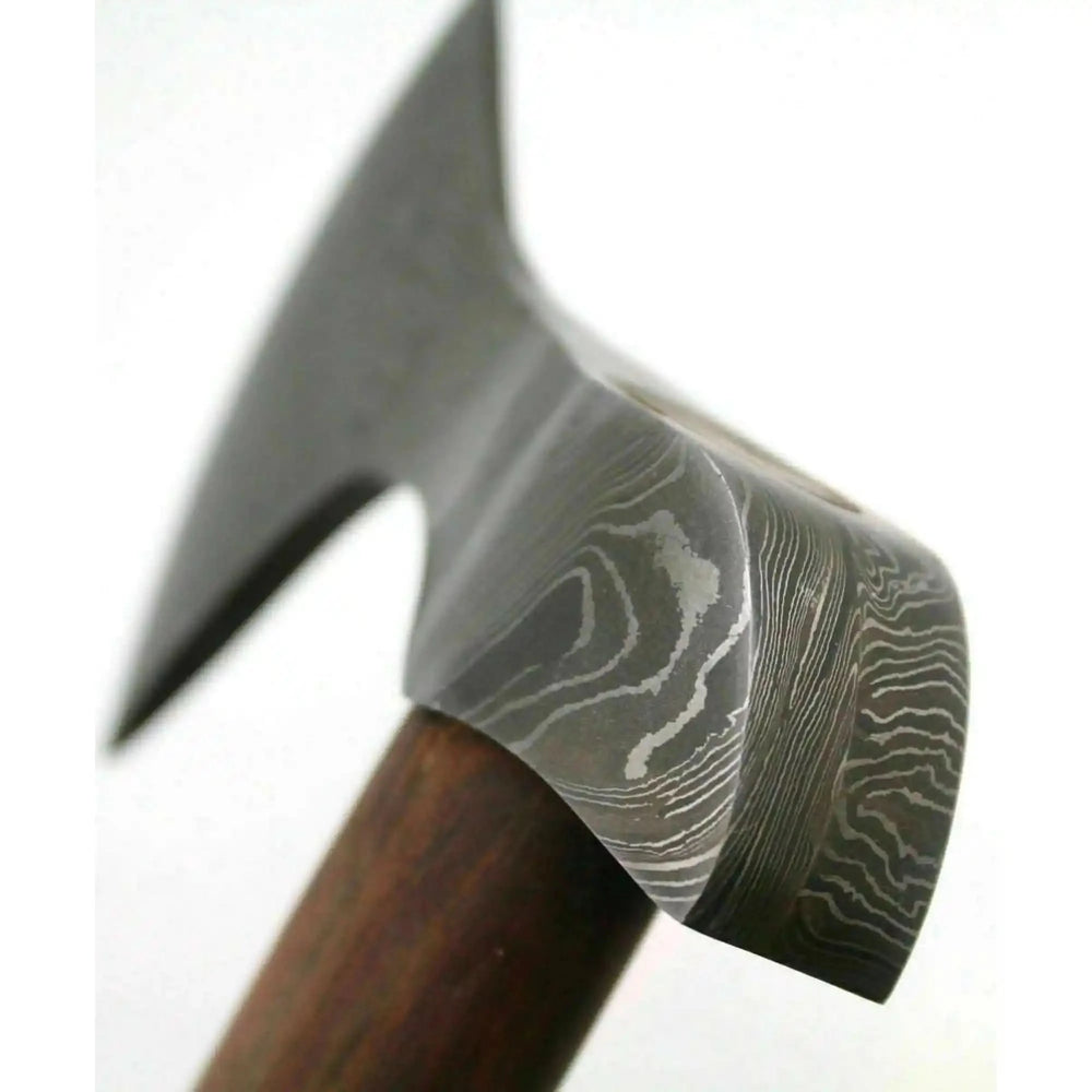     Polished Damascus hunting hatchet with handcrafted wooden handle and stitched leather sheath beside rustic timber logs.