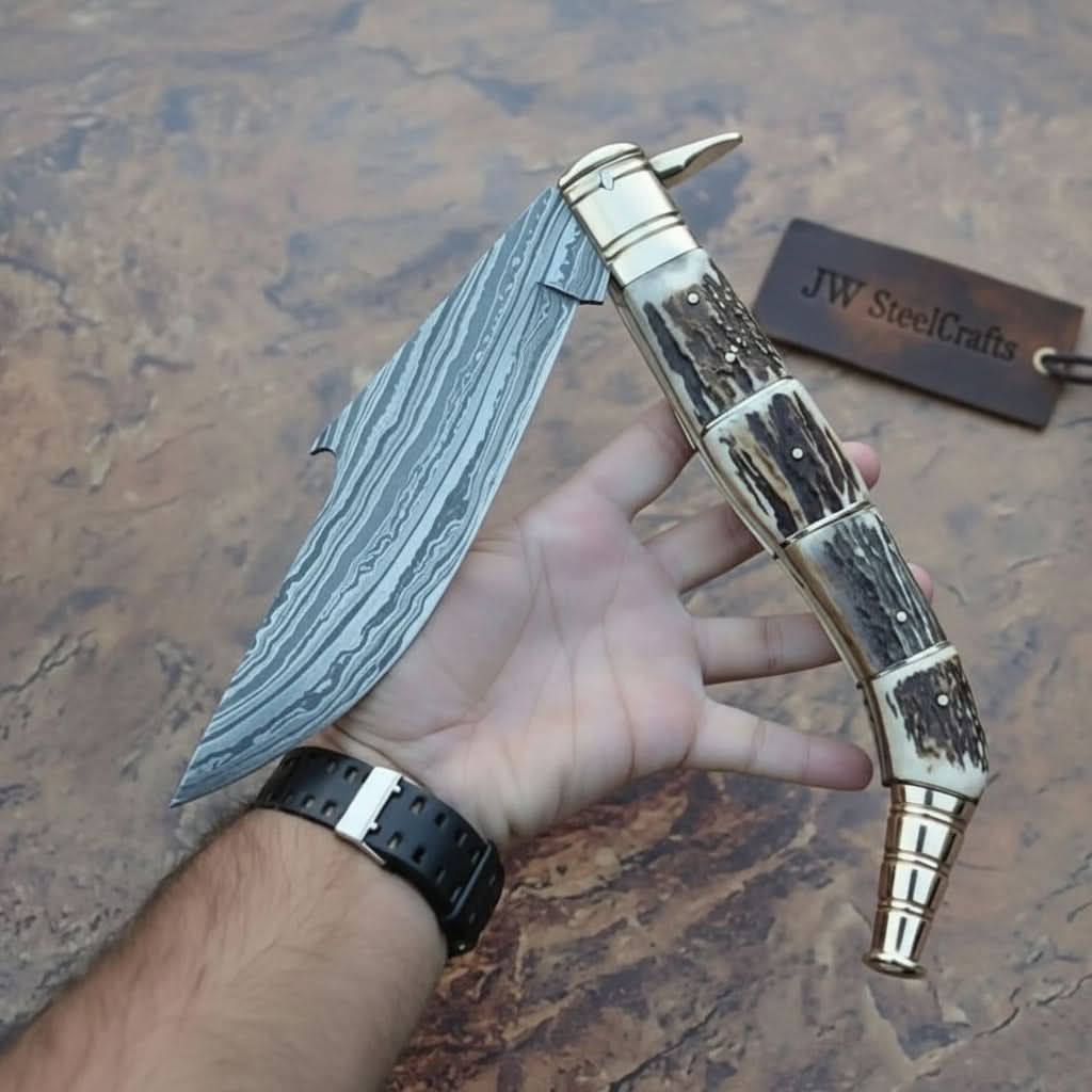     Cedartrail custom Damascus folder with stag scales and wide curved blade shown in hand outdoors