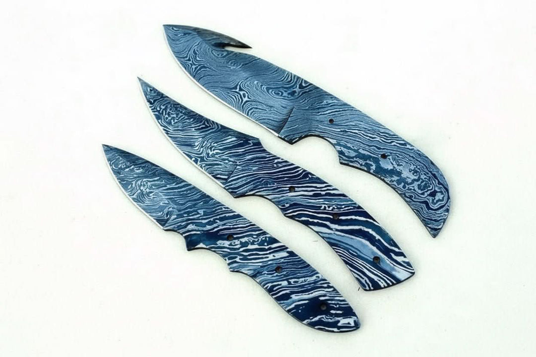 Patterned blue steel knife blanks set with three full tang blades and visible Damascus wave lines.