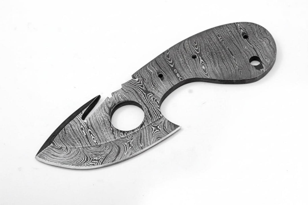 Unfinished Damascus knife blank with gut hook blade, exposed tang, pin holes, and white studio background.